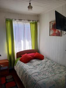 a bedroom with a bed with green curtains and a window at Hospedaje Luna in Valdivia +5 photos