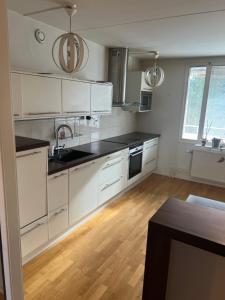 a kitchen with white cabinets and a wooden floor at Lägenhet i Stockholm in Märsta