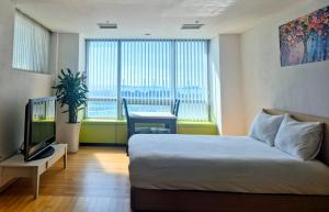 仁川にあるCozy - Experience Home like Comfort Studioのベッドとテレビがあるホテルの部屋