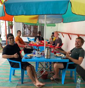 a group of men sitting at a table under an umbrella at Afghan Arya Guest House in Kabul