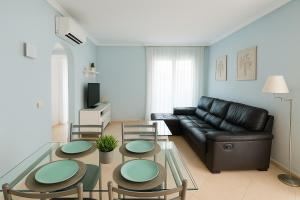 a living room with a black leather couch and a table at Oliva Nova Equestrian Apartment Next to MET Showground in Oliva