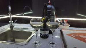 two glasses of white wine sitting next to a sink at Monroe Apartment in Belgrade