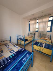 Cette chambre comprend 3 lits superposés et des fenêtres. dans l'établissement TISLIT Surf Taghazout, à Taghazout