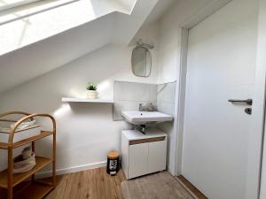 a white bathroom with a sink and a door at 2 Zimmer Dachwohnung mit Burgblick und Kingsize Bett in Freudenberg am Main +24 photos