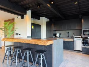 a kitchen with black cabinets and a counter with stools at Exclusive Villa - Lake View - Forest in La Pradera +68 photos
