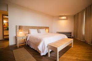 Un dormitorio con una gran cama blanca y un banco. en Bela Vista Hotel Boutique, en Caraíva