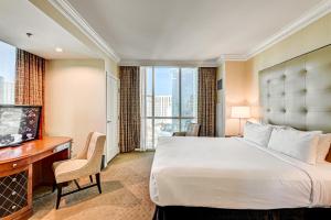a hotel room with a bed and a desk and a television at The Signature at MGM Grand, Luxury Balcony Suite, Strip View in Las Vegas