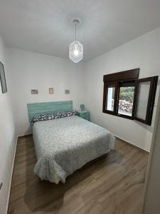 a bedroom with a bed and a chandelier at Casa del arroyo in Caserío Arroyofrío