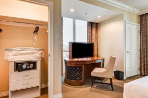 a bedroom with a bed and a desk with a television at The Signature at MGM Grand, Luxury Balcony Suite, Strip View in Las Vegas