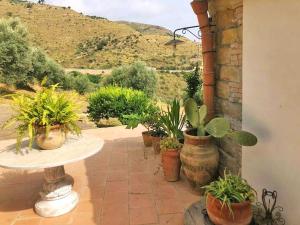 un patio con macetas y una mesa en Nucidda - Country House with sea & mountain views, en Reitano