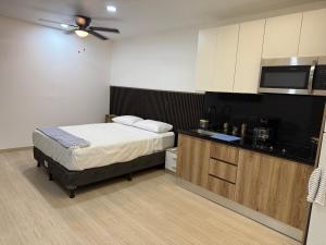 a small bedroom with a bed and a kitchen at Aparta loft Sabana inn in San José