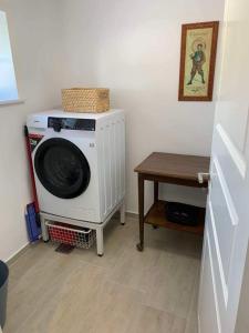 a washing machine in a room with a table at F27-K, 4 people, 4 bedrooms, fully furnished in Aalborg
