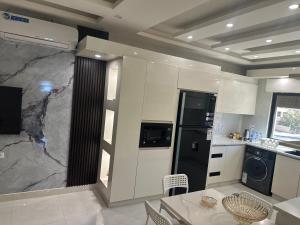 a kitchen with white cabinets and a black refrigerator at Royal house Near Airport in Khuraybat as Sūq +14 photos