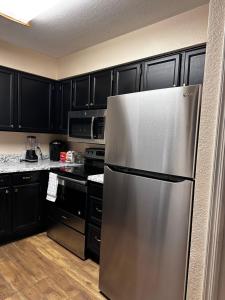 a stainless steel refrigerator in a kitchen with black cabinets at Arizona cozy place in Mesa