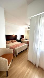 a hotel room with two beds and a chair at Palermo Bridge in Buenos Aires +65 photos