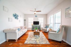 a living room with a couch and two chairs and a tv at Seawall Sunrise-Close to Beach in Galveston