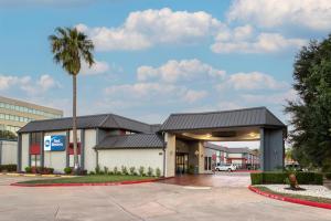 a building with a palm tree in front of it at Best Western Webster Hotel, NASA in Webster