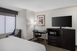 a hotel room with a bed and a desk with a television at Best Western Webster Hotel, NASA in Webster