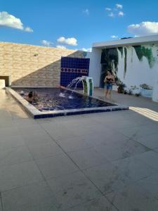 a woman standing next to a pool with a fountain at Casa de Lazer e Eventos Monte Sião in Paulo Afonso +10 photos