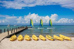 a row of kayaks on a beach with boats in the water at Iberostar Cozumel - All Inclusive in Cozumel