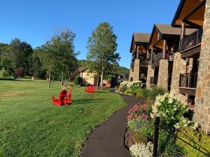a walkway next to a building with red chairs in a park at 2 bedroom condo Ski in Ski out Sommets St-Sauveur in Saint-Sauveur-des-Monts +25 photos
