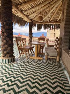 a patio with a table and chairs under a roof at Kasbah Azalay Merzouga takojt in Merzouga