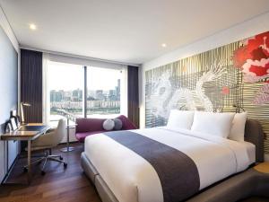 a bedroom with a bed and a desk and a window at Novotel Ambassador Seoul Yongsan in Seoul