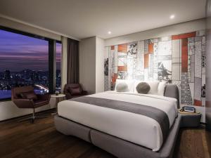 a bedroom with a large bed and a large window at Novotel Ambassador Seoul Yongsan in Seoul +97 photos