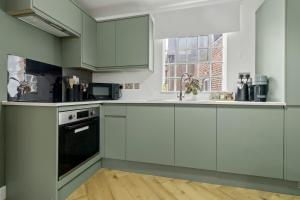 a kitchen with green and white cabinets and a window at Pear Tree - Stylish City Centre Apartment in Worcester