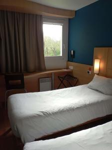 une chambre d'hôtel avec deux lits et une fenêtre dans l'établissement ibis les Etangs des Moines, à Fourmies