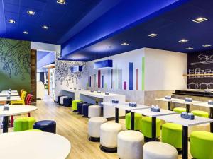 a restaurant with white tables and green chairs at ibis budget Curitiba Aeroporto in São José dos Pinhais