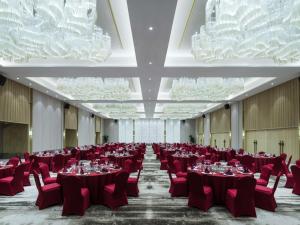 a banquet hall with red tables and chairs and chandeliers at Pullman Zhouzhuang in Kunshan +74 photos