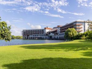 a building next to a lake with a grass field at Pullman Zhouzhuang in Kunshan