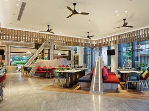 a restaurant with couches and tables and chairs at ibis Styles Batam Nagoya in Nagoya