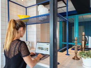 a woman standing at a counter with a laptop computer at ibis budget Pertuis Portes du Luberon in Pertuis