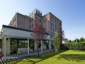 a building with a lawn in front of it at Hotel Ibis Firenze Prato Est in Campi Bisenzio