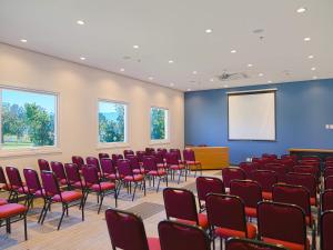 a conference room with red chairs and a screen at ibis Igrejinha in Igrejinha