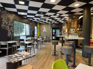 a restaurant with tables and stools in a room at ibis budget Angoulême Centre in Angoulême
