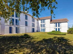 un gran edificio blanco con un gran patio en Greet Hôtel Dijon Sud Longvic, en Longvic