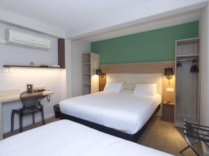 Una habitación de hotel con dos camas y un escritorio. en Greet Hôtel Dijon Sud Longvic, en Longvic