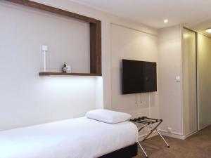 Un dormitorio con una cama y un televisor de pantalla plana. en Greet Hôtel Dijon Sud Longvic, en Longvic