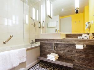 a bathroom with a tub and a sink and a mirror at ibis Styles Lyon Sud Vienne in Chasse-sur-Rhône +87 photos
