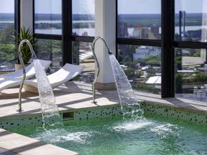 a swimming pool with two chairs and two water fountains at Mercure Rosario in Rosario