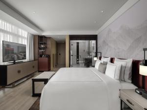 a bedroom with a large white bed and a television at Swissôtel Clark Philippines in Clark
