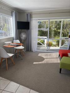 a living room with a table and chairs at Ash Grove Boutique Motel in Paihia
