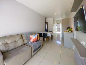 Una sala de estar con un sofá y una cocina. en Curta Praia de Armação - Casa Orquídea, en Penha