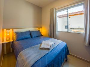 Un dormitorio con una cama con sábanas azules y una ventana. en Curta Praia de Armação - Casa Orquídea, en Penha