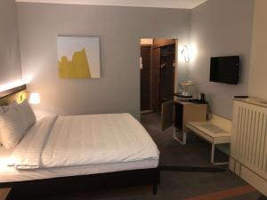 Un dormitorio con una cama, un escritorio y un televisor. en Mercure Galati Centrum, en Galaţi