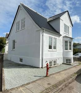 a white house with a red fire hydrant in front of it at F27-1 3 people, 3 bedrooms, fully furnished in Aalborg