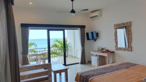 a bedroom with a bed and a balcony with the ocean at Mejore Beach Hotel in Amed